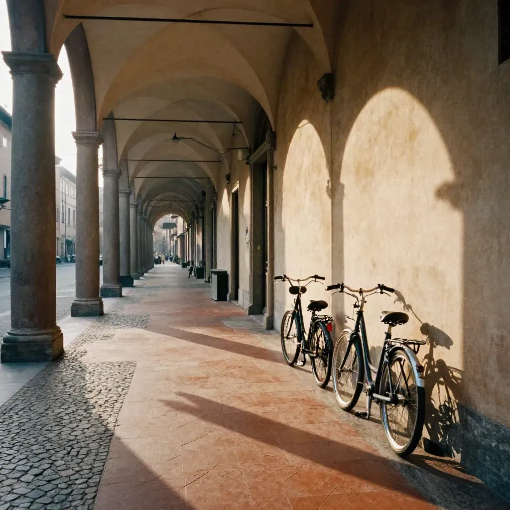 Portico bolognese in cotto con biciclette e luce radente tra le arcate